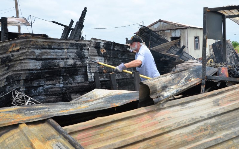 John Chandler pokes around the wreckage of the fire that engulfed The Cookie Jar off of US Highway 77A on Sunday afternoon.