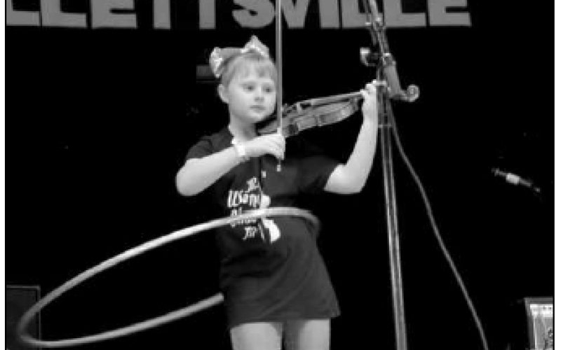 Photo by Hans Lammeman McKenna Peterson focuses while playing a melody on her fiddle and balancing a Hula-Hoop at the 51st annual Texas State Championship Fiddlers Frolics.