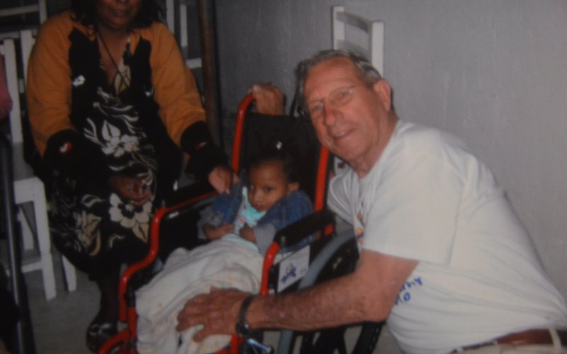 Bill Lopez poses with a child in a donated wheelchair through a Rotary program in Peru in the early 2000s. Contributed Photo.