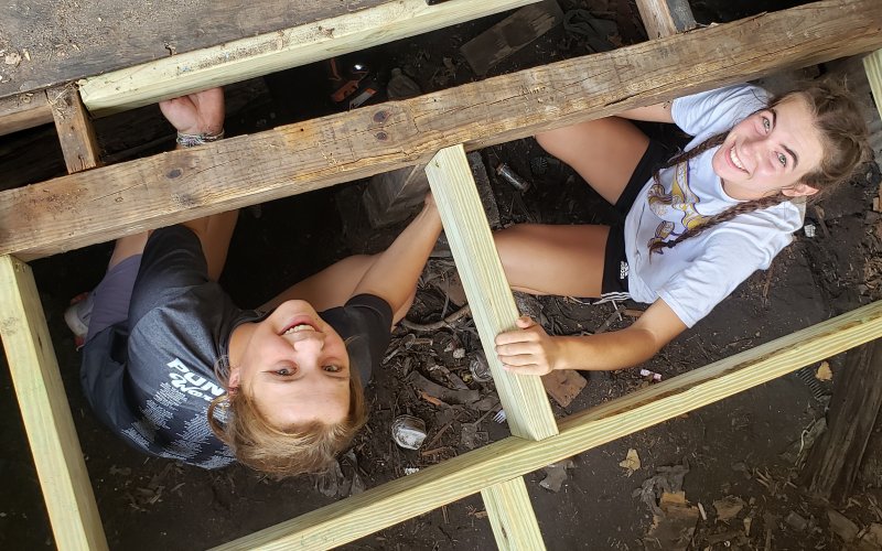Lauren Faldyn and Kailey Boedeker truly got into their work project, seeking out bad boards in the supports of an old porch and replacing them with new wood to prolong the life of the structure. Photos by Bobby Horecka