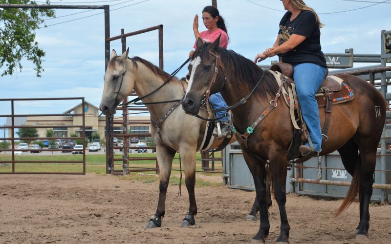 Brittani Richter (left) and Kim Chandler talk on horseback at the Yoakum Rodeo Arena Friday, July 15.