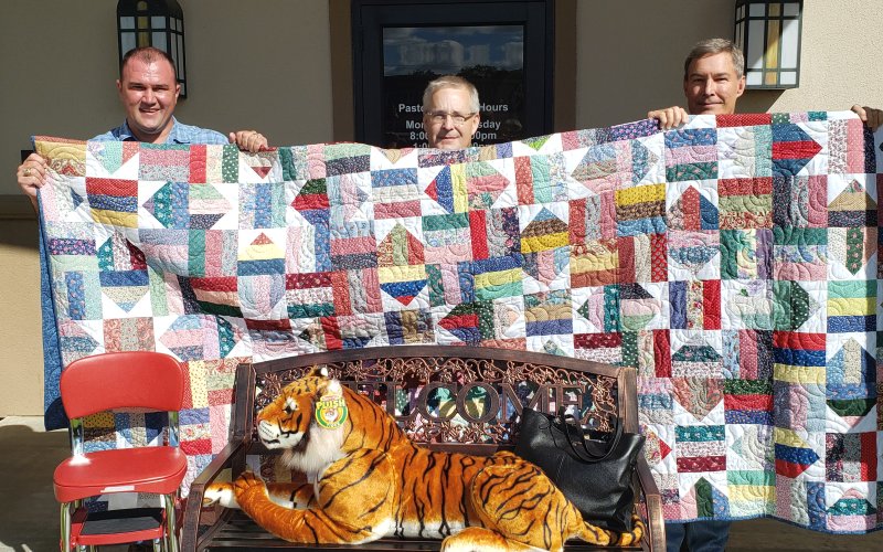 Pictured from left to right are SJS Principal Sean Mooney, Father Matthew Huehlefeld, and Picnic Chairperson Patrick Matusek with some of the auction items.