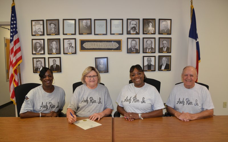 Former Stevens Mayo football standout and National Football League player, the late Andy Rice Sr., was recognized Tuesday, Sept. 6. Hallettsville Mayor Alice Summers signed a proclamation designating the day as Andy Rice Sr. Day. From left witnessing the signing are Andy’s daughter, Andrea (Rice) Smith, Summers, niece, Rachel (Foley) Grayer, and friend, David Smolik. The tee shirts worn by those on the photo are compliments of Minshell Crayton Ford. Photo by Jimmy Appelt