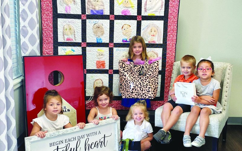 Pictured with some of the auction items are, left to right, Sofie K., Brynn P., Delane A., Adaline K. (standing), Case M., and Haydee G. Contributed photo.