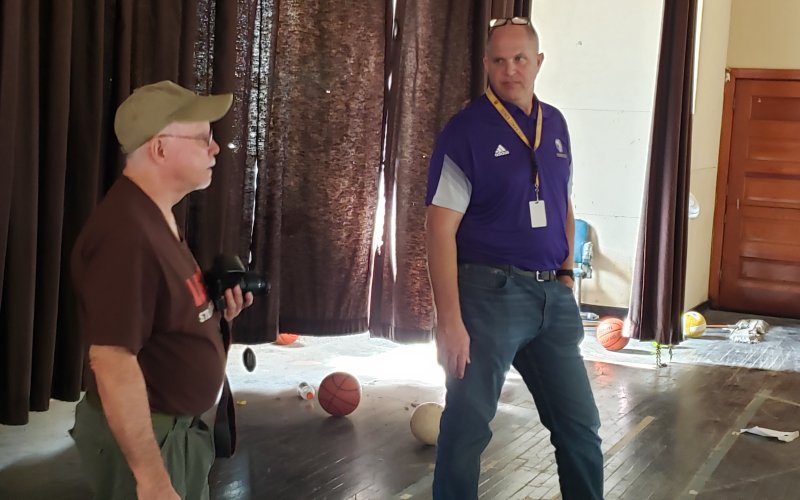 Local historian Doug Kubicek and Shiner superintendent Alex Remschel gave us a tour of the Old Shiner Gym last week. Seen here on the old stage, the two are discussing what all still might need doing to make this a 100% usable facility as it was intended—replacing just one set of curtains for use on the stage runs in the tens of thousands of dollars, all the way around would run in the hundreds of thousands. Remschels said. Even more would be needed to bring the stage lighting up to snuff.