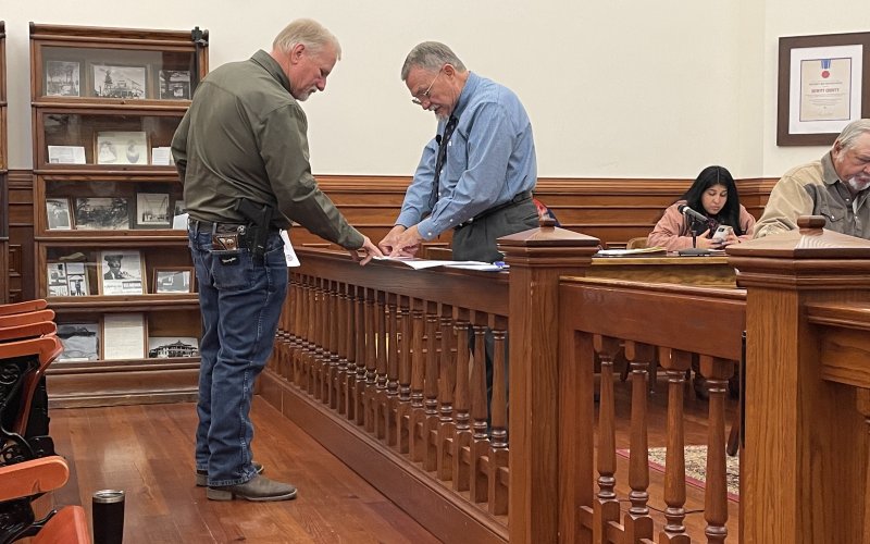 (L-R) Sheriff Carl Bowen and County Judge Daryl Fowler inspect an agreement at last Monday’s commissioners court meeting.