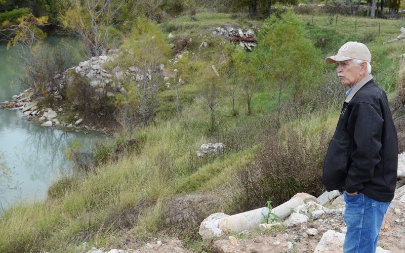 Curtis Afflerbach looks toward the Guadalupe River that deposited a large metal tank onto land north of State Highway 72 in Cuero.