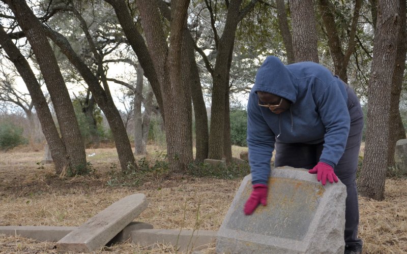 Yoakum Memorial Association President Vanitia Cheeves wipes a headstone at the Yoakum City Colored Cemetery on Monday, Jan. 23.