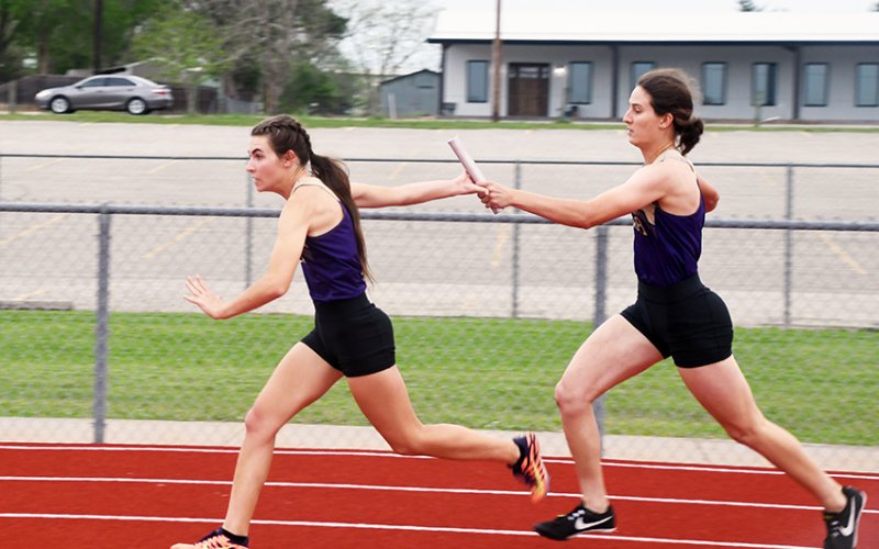 Lauren Faldyn (left) take the baton from Rylee Vancura during the 400-meter relay. Shiner girls won all three varsity relay races. Photo by Mark Lube.