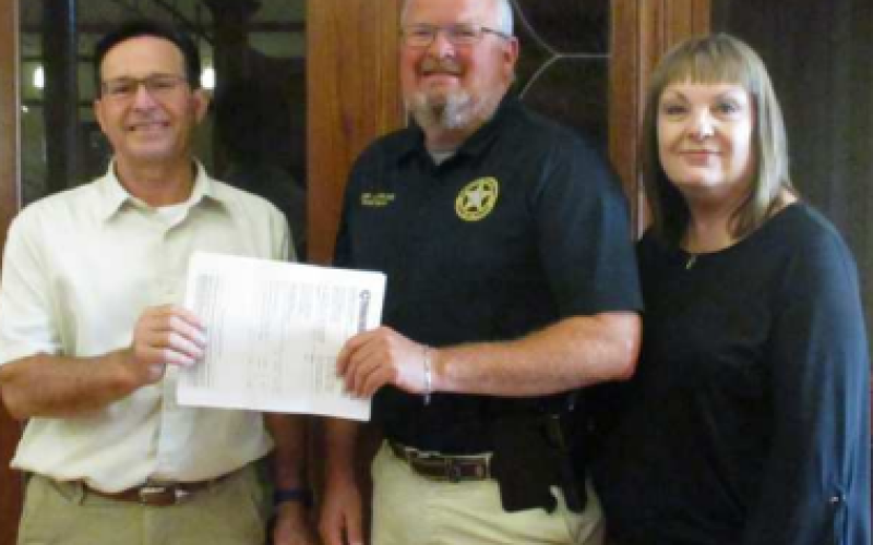 Police Chief Daniel Beyer and City Administrator Lu Ann Rogers receive a generous donation from SouthStar bank board president David Kapavik.
