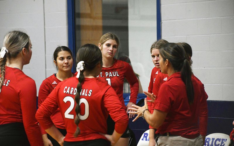 The Lady Cardinals volleyball team meets with head coach Nicco Brown (right) prior to a match in the Rice Tournament on Thursday. Photo by Mark Lube.