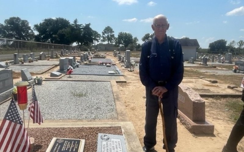 August Janak stands next to his parent’s gravestones, where a plaque was set honoring his brothers who served in the U.S. Army.