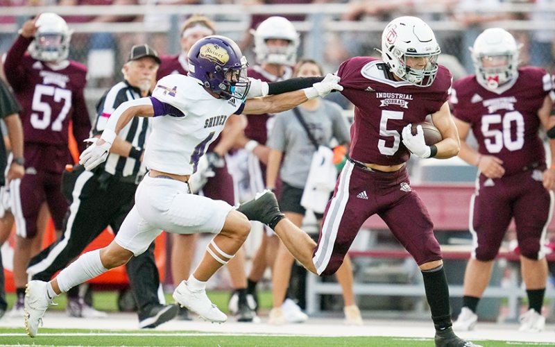 Shiner defensive back Jordan Harrison (left) attempts to grab ahold of Industrial’s Nic Kuchler Friday night in Industrial. Photo by Howard Esse.
