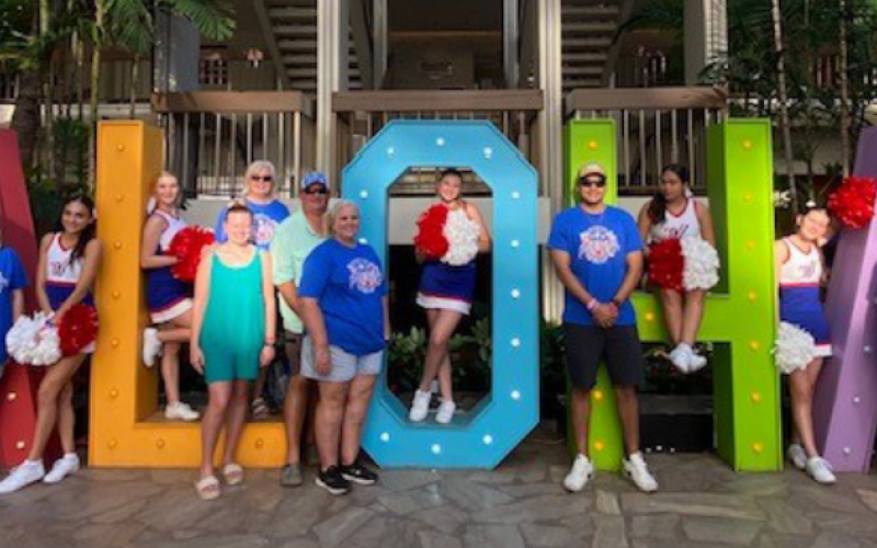 Above, the Moulton cheerleaders pose with their parents and sponsors in front of the Aloha State sign in Hawaii. And at left, starting top row from left, cheerleaders attending the Pearl Harbor Day parade performance were Valeria Pinedo, Abygail Tinajero and Abigail Siegal, and bottom from left, Katie Richter and Samantha Michal.