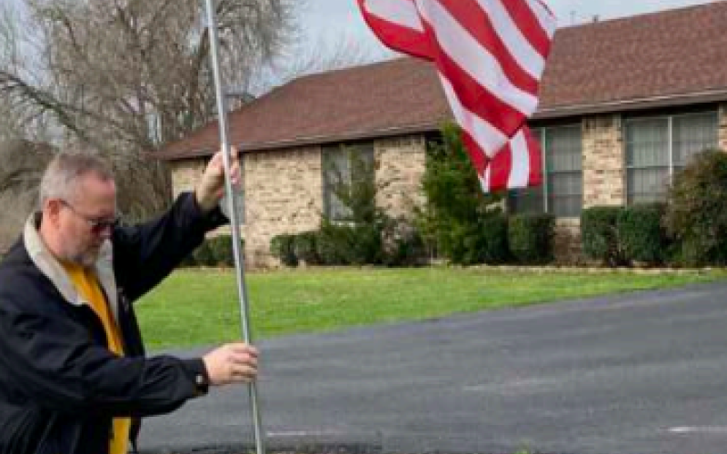 Lion James Reeves, an Air Force veteran who served in the Middle East after the Gulf War, helps place flags around town.
