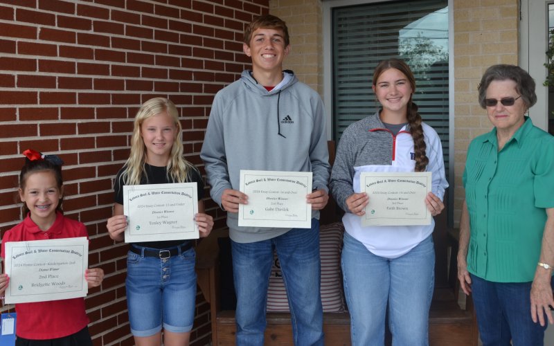 Shiner Catholic Schools had four students place in the Lavaca Soil and Water Conservation District poster and essay contest. From left are Bridgette Woods, whose poster placed second in district in the K-2nd division, Tenley Wagner, whose essay placed first in the 13 and under division, Gabe Darilek, whose essay placed second in the 14 and over division, Faith Brown, whose essay placed third in the 14 and over divisions, and LSWCD secretary Dorothy Henke. Photo by Jimmy Appelt