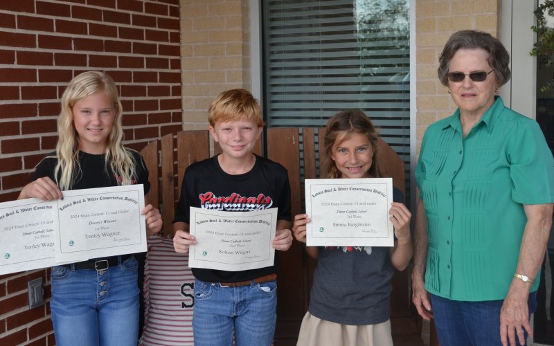 Lavaca Soil and Water Conservation District 13 selected its school wide 13 and under essay winners from Shiner Catholic School, who include from left Tenley Wagner (1st), Kolton Wilgus (2nd), Emma Bargmann (3rd) and LSWCD secretary, Dorothy Henke. Photo by Jimmy Appelt
