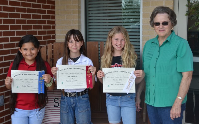 Lavaca Soil and Water Conservation District 13 selected its school wide 3rd–6th poster winners from Shiner Catholic School, who include from left Elana Basquez (1st), Jesslyn Garrett (2nd), Brooke Hermann (3rd) and LSWCD secretary, Dorothy Henke. Photo by Jimmy Appelt