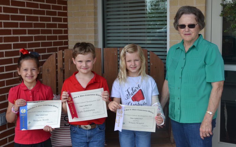 Lavaca Soil and Water Conservation District 13 selected its school wide K-2nd poster winners from Shiner Catholic School, who include from left Bridgette Woods (1st), Cade Halliburton (2nd), Teagan Wagner (3rd) and LSWCD secretary, Dorothy Henke. Photo by Jimmy Appelt