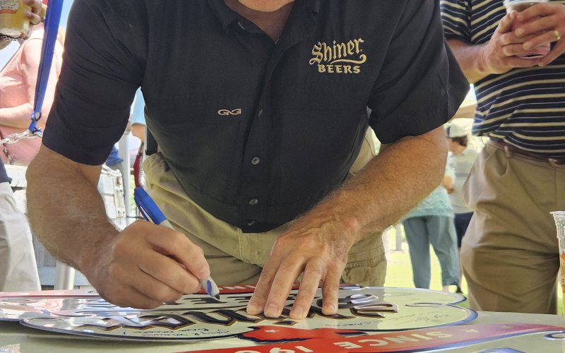 Jimmy Mauric adds his signature to a Shiner Beers sign.