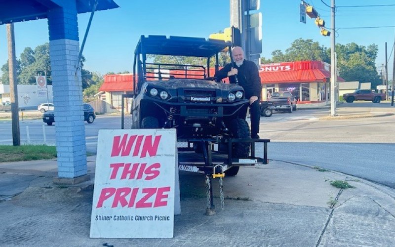 Father Bryan Heyer is shown with the first place raffle prize, a 2024 Kawasaki Mule Pro FXT. This mule includes a 12 ft. utility trailer, generously donated by Boehm Tractor Sales. Photo by Clayton Kelley.