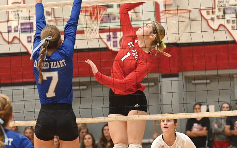 Riley Mozisek (right) jumps up to contact a set while Sacred Heart’s Rylan Dworsky attempts a block. St. Paul libero Tatum Walker looks on. Photo courtesy of Chuck Grafe/Hallettsville Tribune-Herald.