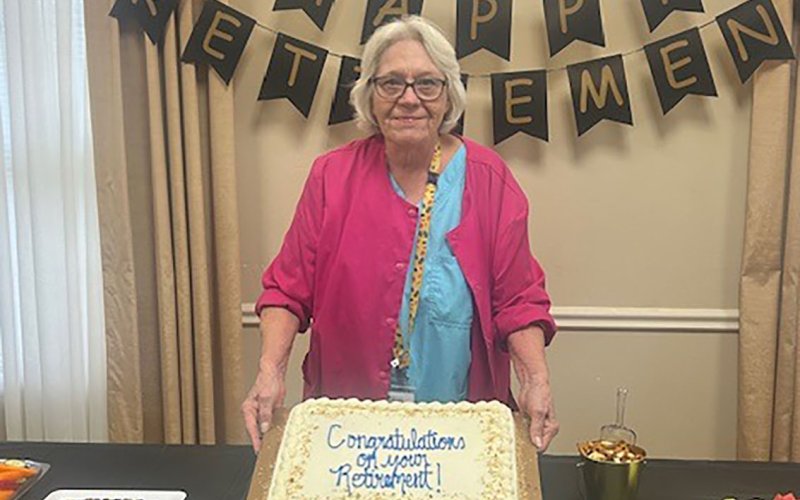 Virginia Vincik poses with her retirement cake at a party held in her honor. Photo by Clayton Kelley