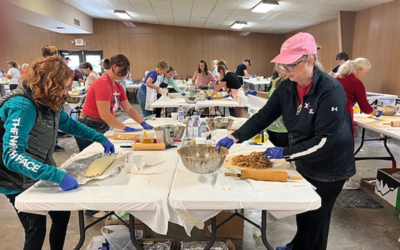 Parishioners and volunteers are shown filling and rolling up strudels.