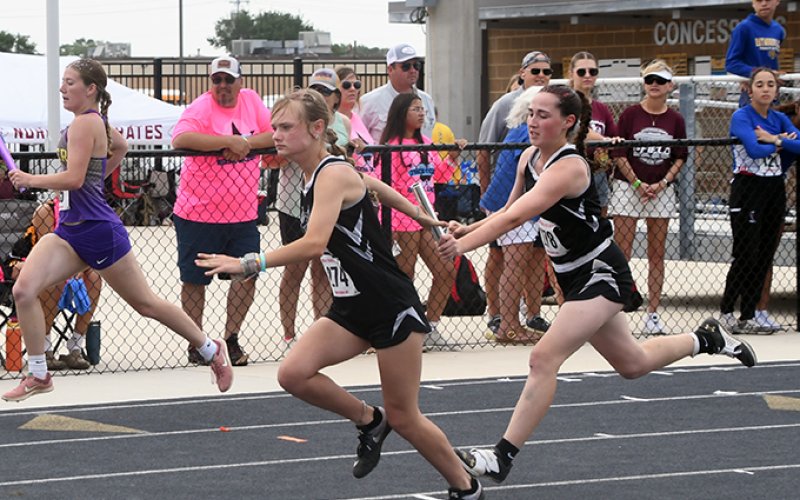 Karsyn Blahuta (left) accepts the handoff from Addison Simper during the 400-meter relay.  The Kittens advanced to state with second place in a time of 52.88 seconds.