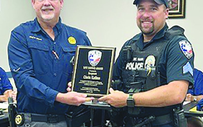 Sgt. Chris Kalina, right, was recognized for saving a woman from a house fire that occurred in early April. Police Chief Wayne Denson presents him with a plaque. Not pictured is Officer William Miller, who assisted in that call. Photo by Clayton Kelley.
