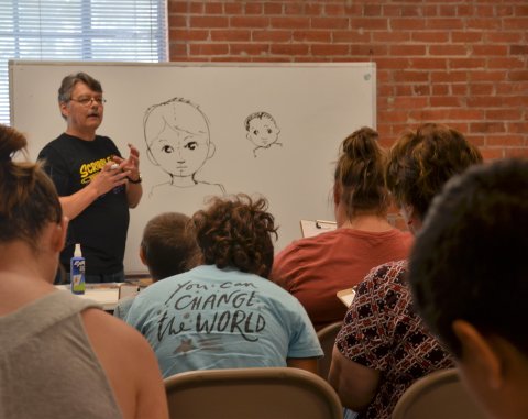 Professional cartoonist David Pitts demonstrates techniques for drawing faces at the Carl and Mary Welhausen Library June 7.