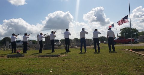 Members of Post No. 392 line up for a 21-gun salute and performance of TAPS beneath a half mast Memorial Day flag, lowered out of respect to the many lives lost last week in Uvalde.