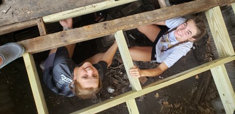 Lauren Faldyn and Kailey Boedeker truly got into their work project, seeking out bad boards in the supports of an old porch and replacing them with new wood to prolong the life of the structure. Photos by Bobby Horecka