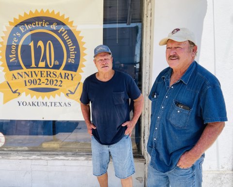 C.L. (Left) and E.L. Moore stand outside their shop with a sign displaying 120 years of service. Photo by Hans Lammeman.