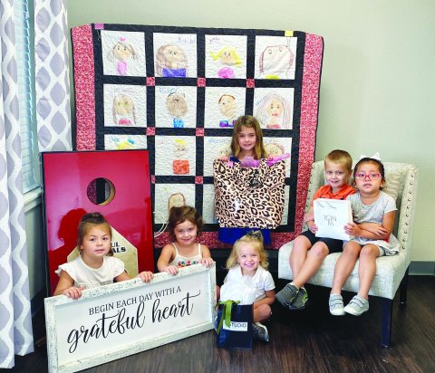 Pictured with some of the auction items are, left to right, Sofie K., Brynn P., Delane A., Adaline K. (standing), Case M., and Haydee G. Contributed photo.