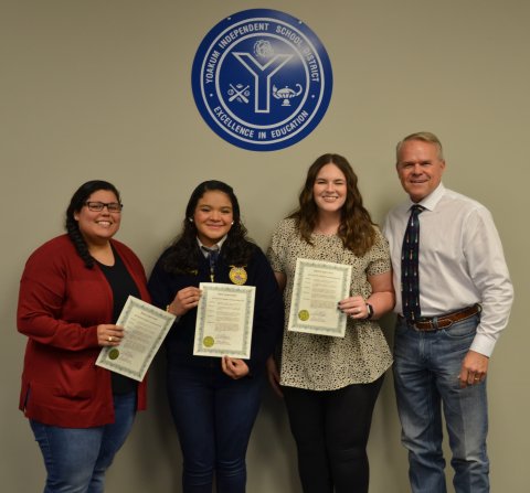 (From left) Adriana Bridges, Jenny Lopez, Laura Johnson and Yoakum ISD School Board President Glen Kusak pose during the Dec. 12 YISD board meeting.  Photo by Hans Lammeman. 