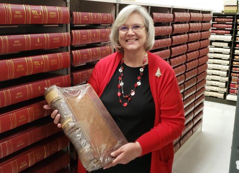 With the oath of office administered Sunday morning at the Lavaca County Courthouse to several new county officials, including her replacement, Elizabeth Kouba officially begins her retirement after 42 years of public service to its citizenry. She's holding one of the original county record ledgers. Behind her are racks and racks of the improved versions she's done during her tenure. Photo by Bobby Horecka