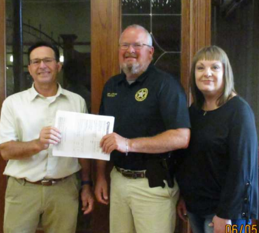 Police Chief Daniel Beyer and City Administrator Lu Ann Rogers receive a generous donation from SouthStar bank board president David Kapavik.