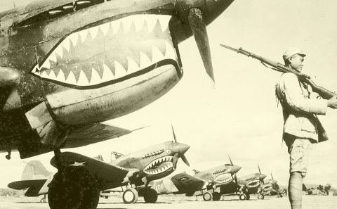 Chinese soldier guards a squadron of P-40 fighter planes, decorated with the typical shark face of the Flying Tigers, lined up at an unknown airbase in China in 1943. Photo courtesy of National Archives and Records Administration