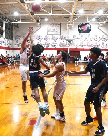Jackson Seibert (left) heaves the ball toward the basket with Sam Perez on the play as well  in the second half of St. Paul’s game against Faith Academy on Nov. 5. Seibert bucketed six points in the Cardinals 43-30 win. Photo by Mark Lube.