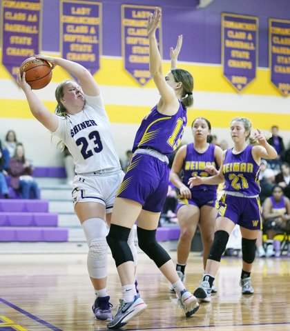 Kailey Boedeker plays “keep away” against a Weimar defender Friday in Shiner. She had a great performance, hitting five treys and scoring 16 points to lead Shiner. Photo courtesy of Howard Esse.