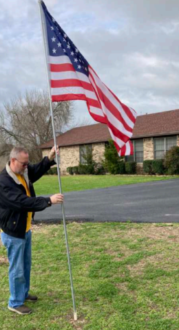 Lion James Reeves, an Air Force veteran who served in the Middle East after the Gulf War, helps place flags around town.