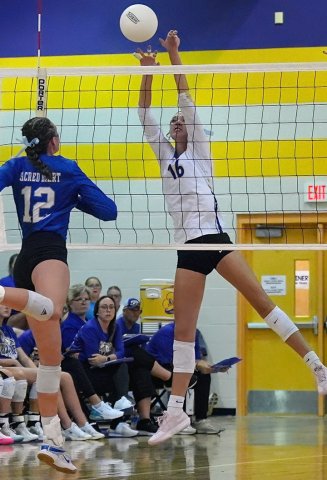 Senior Morgan Lenehan (left) gets up for a block in the Aug. 20 win against Sacred Heart. Photo courtesy of Howard Esse.