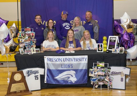Dyllan Chrismon (seated, middle) will attend Nelson University and play pitcher/first base for the Lions softball team. Also shown is seated left, Kayden Chrismon and right GracynChrismon. Standing from left are assistant softball coach Patrick Walker, assistant coach Anastacia Rehak, Clint Chrismon, Terri Chrismon and head coach Jason Keller. Photo courtesy of Photos by Lori Raabe.