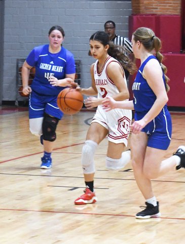 Sacred Heart players guard Nora Koch (center) as she advances the ball down court during the first half of Friday’s St. Paul win. Photo by Mark Lube.