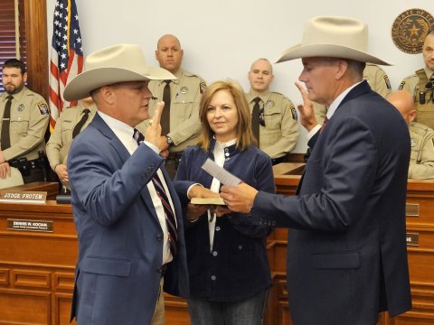 With wife Kim at his holding a Bible he was given by a fellow law enforcement officer 19 Christmases ago, Steven Greenwell accepts his oath of office in a ceremony led by Goliad County Sheriff Roy Boyd. Photo by Bobby Horecka