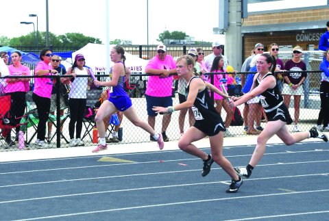 Karsyn Blahuta (left) accepts the handoff from Addison Simper during the 400-meter relay.  The Kittens advanced to state with second place in a time of 52.88 seconds.  Photo by Mark Lube.