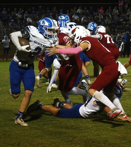 Cardinal Tyler Pendley grabs ahold of Indian running back Ty Noska during the St. Paul’s home game with Sacred Heart on Friday. The Indians won 27-20 for their third win in a row in the series. Photo by Mark Lube.