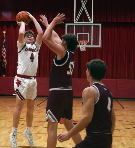 A pair of East Bernard players try to disrupt the shooting of Cardinal Jace Matias during the first half. Matias scored six points in the 64-46 St. Paul win. Photo by Mark Lube.