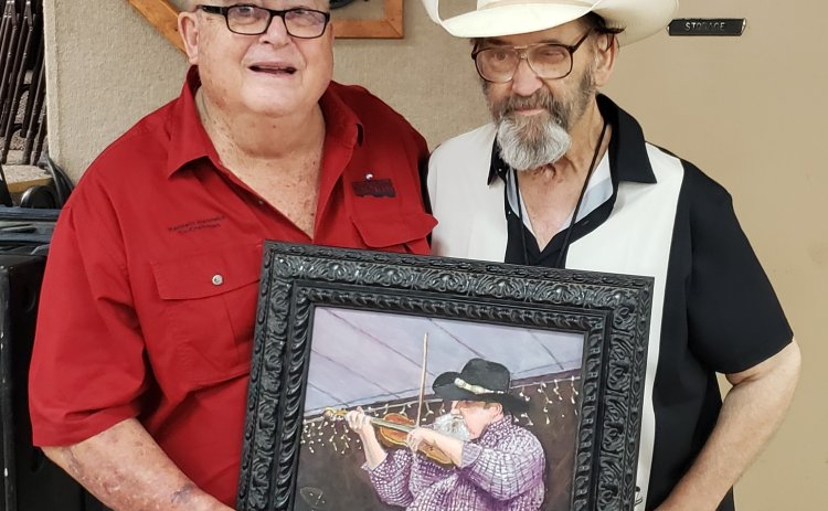 Kenneth Henneke, one of the founders of the annual Fiddlers Frolics in Hallettsville, poses with Keith Junot shortly after his Hall of Fame induction at the 50th annual Frolics held in 2021. Junot played what becanme the very first Frolics held at Wied Hall when he was just 12, already impressing those gathered with his talents. He clutches a potrait of him as a younger man that Sheridan artist Dennis Pesek painted presented to him at his induction ceremony.